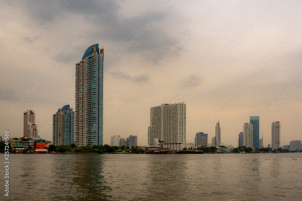 Residential , commercial and business buildings next to the river with overcast sunset sky