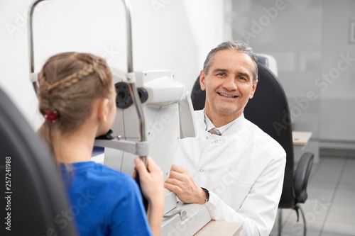 Experienced ophthalmologist doing checkup on slit lamp.