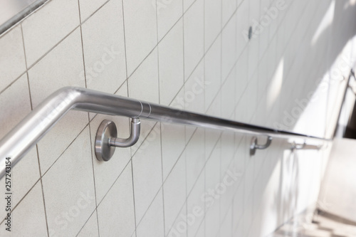 Photo stainless steel handrail on ceramic wall.