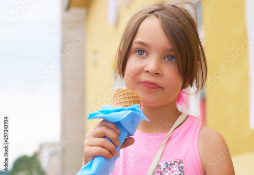 Pretty little girl eating licking big ice cream in waffles cone happy laughing on nature background