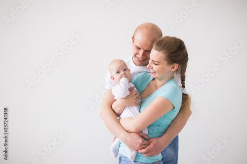 Proud mother and father smiling at their newborn baby daughter over white background with copy space