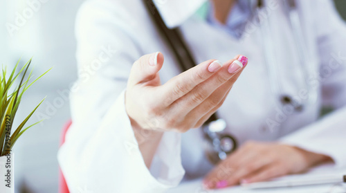 Female doctor explaining patient symptoms or asking a question as they discuss together in a consultation. Just hands over the table.