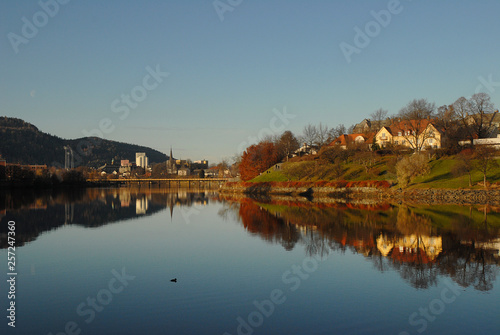 Calm river, Nidelven, that flows through Trondheim City in beautiful autumn weather. The landscape is reflected in calm water.