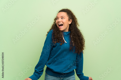 Teenager girl over green wall smiling