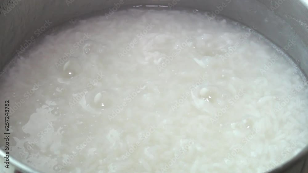 Slow motion surfact of boiling water to cook rice in a stainless steel pot at the kitchen