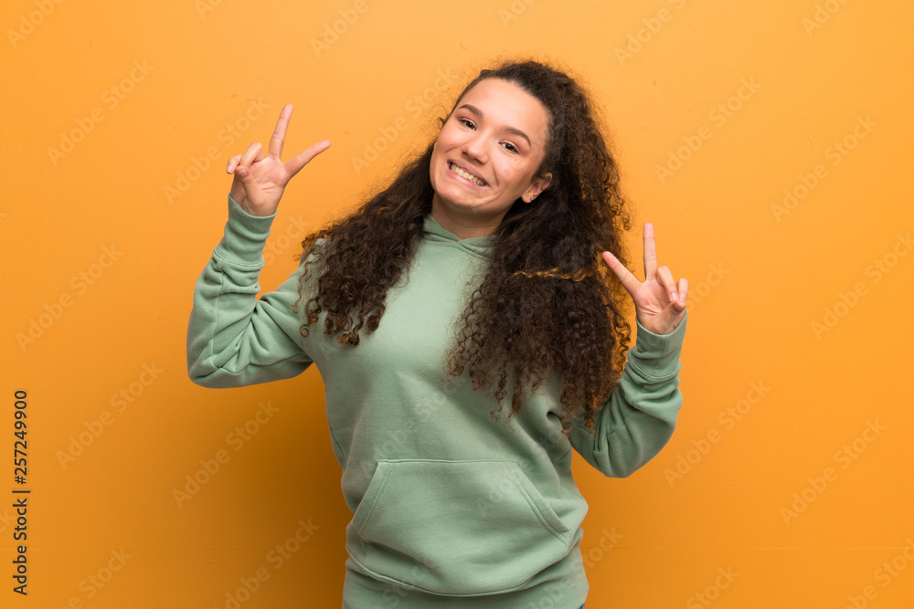 Teenager girl over ocher wall showing victory sign with both hands Teenager girl over ocher wall showing victory sign with both hands
