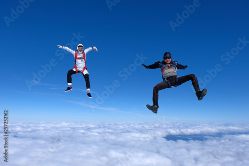 Two guys are falling above white clouds.