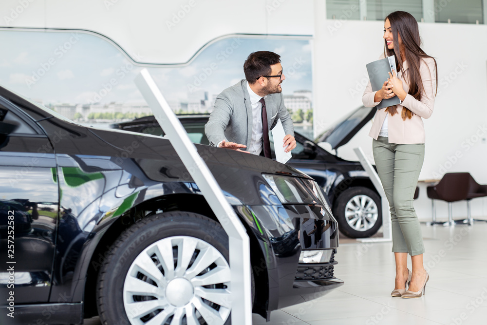 Salesman presenting a brand new car to a female buyer Salesman presenting a brand new car to a female buyer