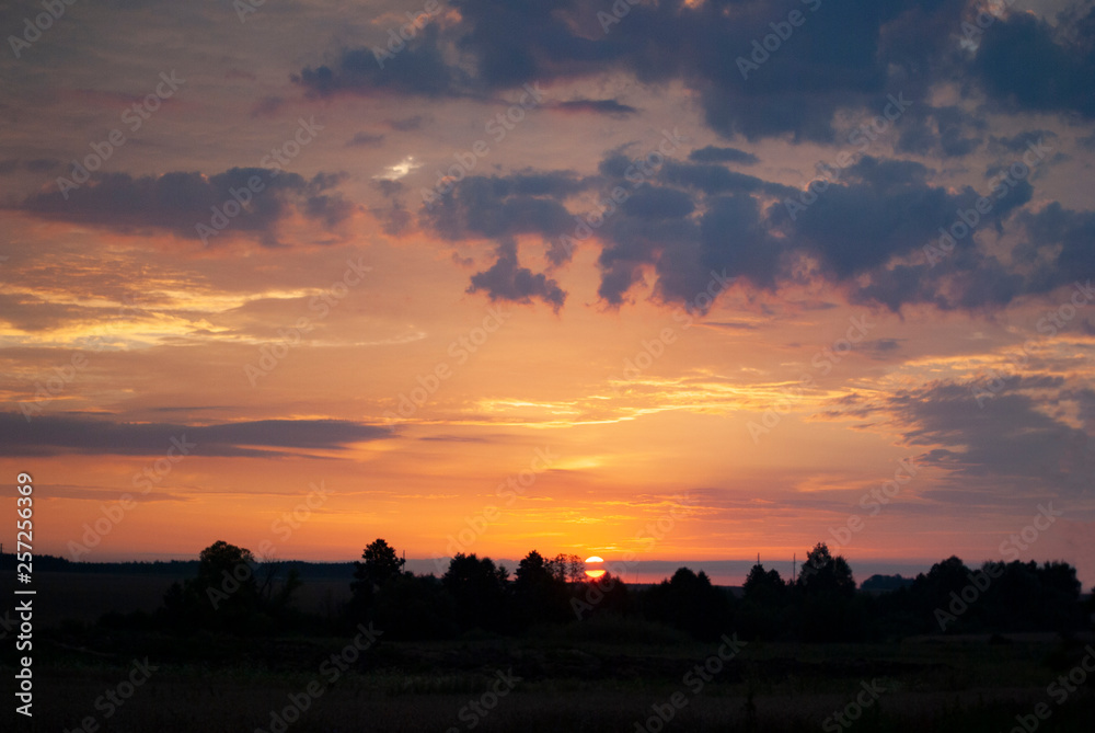 View of a Beautiful Sunset and Sky with dramatic clouds over a Silhouetted Land Horizont.