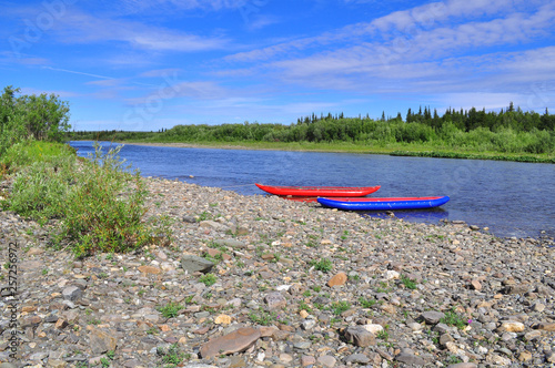 Tourist kayaks at pebble river banks.