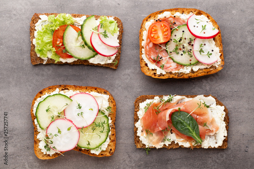 Sandwich with cereals bread and salami on dark marble background.