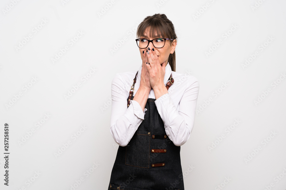 Young woman with apron nervous and scared putting hands to mouth Young woman with apron nervous and scared putting hands to mouth