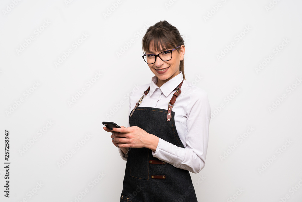 Young woman with apron sending a message with the mobile