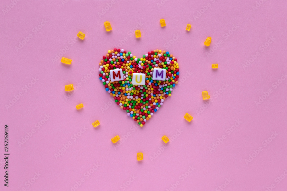 Heart shape made of hundreds and thousands on a pink background