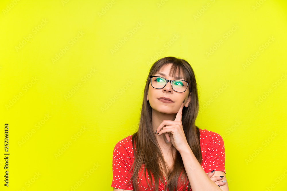 Young woman over green wall thinking an idea Young woman over green wall thinking an idea