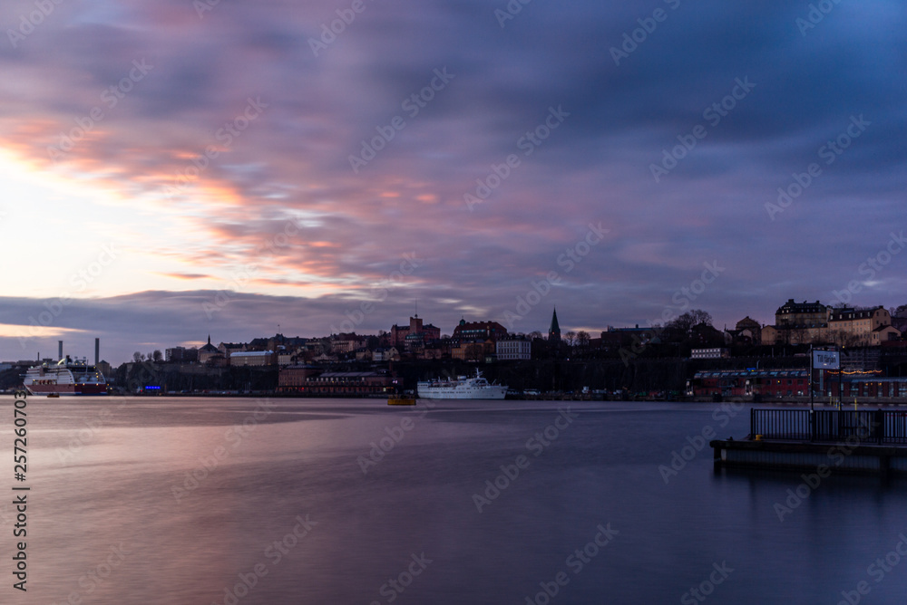 A red, colorful sunrise on the sea in the harbor of  Stockholm in winter  with the backdrop of the Old Town  with the sign 