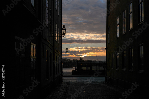 Sunrise sun filtering through on the old cobbled narrow street with colorful houses in Stockholm in the morning - 1