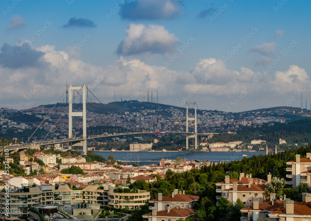 Bosphorus Bridge. Bridge over the Bosphorus in Istanbul. View from the European part of Istanbul against the blue sky with clouds and the hills of the Asian part - Üsküdar district
