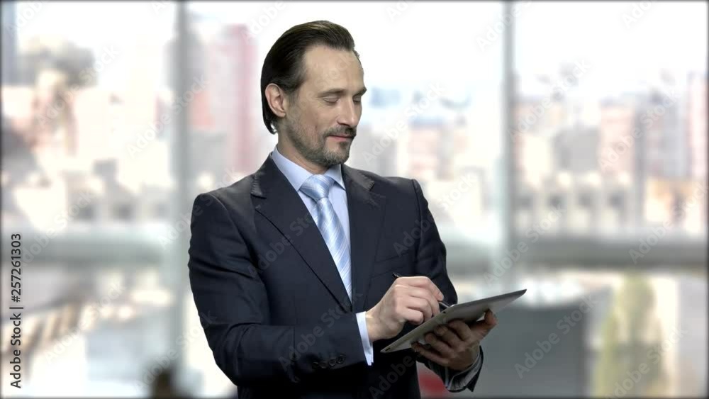 Male caucasian architect using digital tablet. Handsome middle-aged businessman working on pc tablet. Blurred city background. Male caucasian architect using digital tablet. Handsome middle-aged businessman working on pc tablet. Blurred city background.