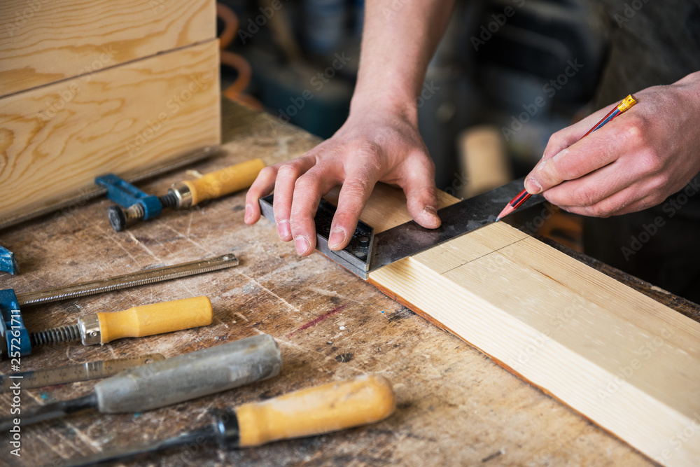 The worker makes measurements of a wooden board with ruler. The worker makes measurements of a wooden board with ruler.