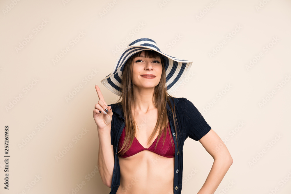 Woman in bikini on ocher background pointing with the index finger a great idea Woman in bikini on ocher background pointing with the index finger a great idea