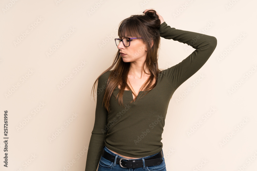Young woman on ocher background having doubts while scratching head Young woman on ocher background having doubts while scratching head