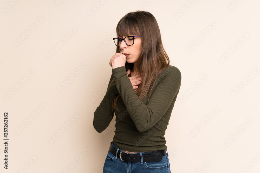 Young woman on ocher background is suffering with cough and feeling bad Young woman on ocher background is suffering with cough and feeling bad