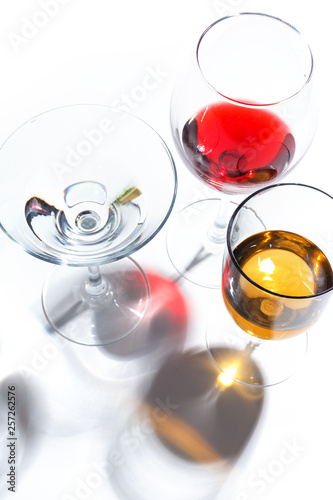 Glass glasses with drinks of different colors on a white background. Top view. The concept of an alcoholic cocktail.