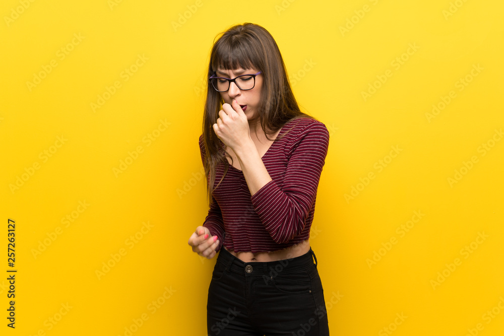 Woman with glasses over yellow wall is suffering with cough and feeling bad Woman with glasses over yellow wall is suffering with cough and feeling bad