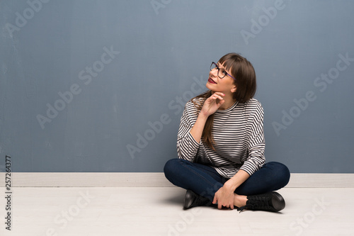 Woman with glasses sitting on the floor thinking an idea while looking up
