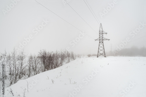 between the wooden supports stretched electrical wires. winter landscape and fog © Roman