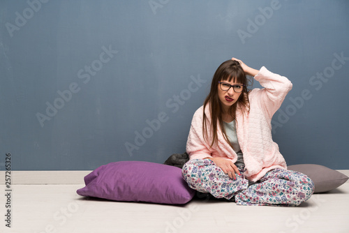 Woman in pajamas on the floor with an expression of frustration and not understanding