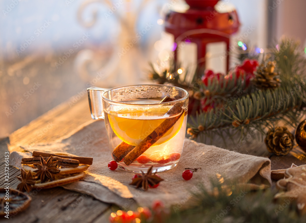 Winter theme. Christmas tea with spices, cup of tea with orange, cinnamon, anise, cookies in a shape of star, pepper and gray scarf on wooden background. Flat lay, View from above. Copy space for text Winter theme. Christmas tea with spices, cup of tea with orange, cinnamon, anise, cookies in a shape of star, pepper and gray scarf on wooden background. Flat lay, View from above. Copy space for text