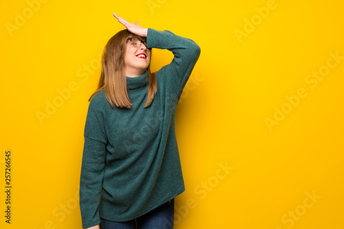 Woman with glasses over yellow wall has just realized something and has intending the solution © luismolinero