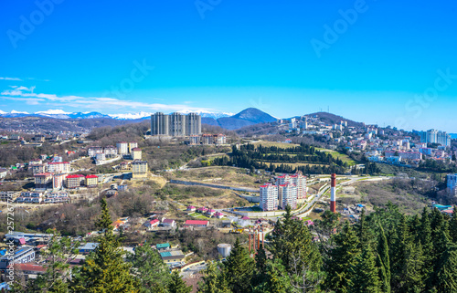 Blue coast of Black Sea in Sochi with houses under summer cloudy sky