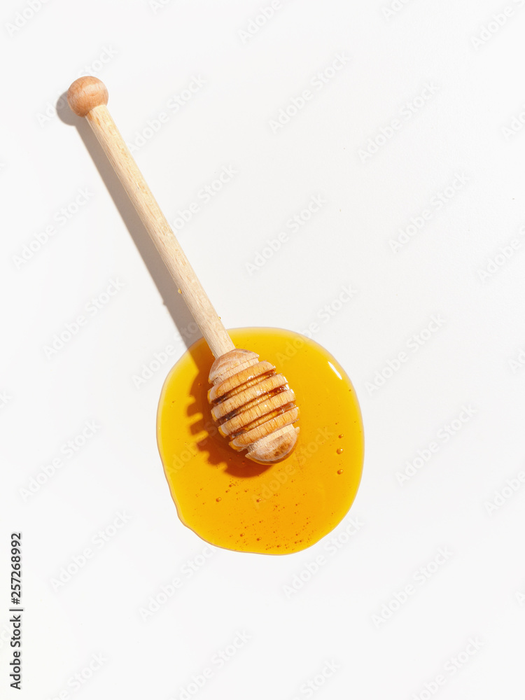 Wooden spoon for honey and spilled honey on a white background. Top view. Wooden spoon for honey and spilled honey on a white background. Top view.