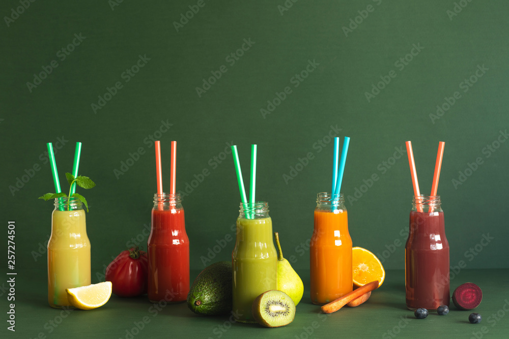Composition of healthy and useful colorful vegetable juices and smoothies with chia and flax seeds in glass bottles, set on the green background, copy space. Lifestyle, diet, body balance. 
