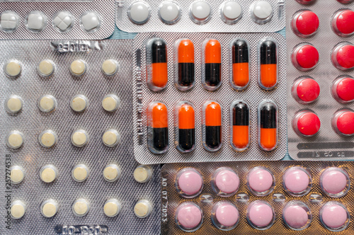 Multicolored tablets and capsules in blisters close-up, top view. The concept of treating human diseases photo