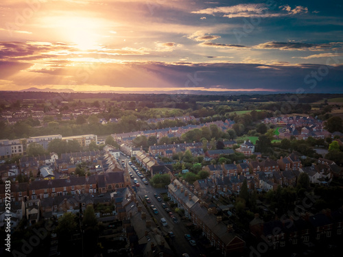 Sun setting with atmospheric effect over traditional British houses and tree lined streets. Dramatic, warm lighting creates a homely mood