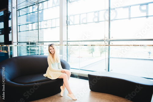 Portrait of a beautiful young blonde sitting on the couch by the window of the business center Free Download Portrait of a beautiful young blonde sitting on the couch by the window of the business center - GFXLoad