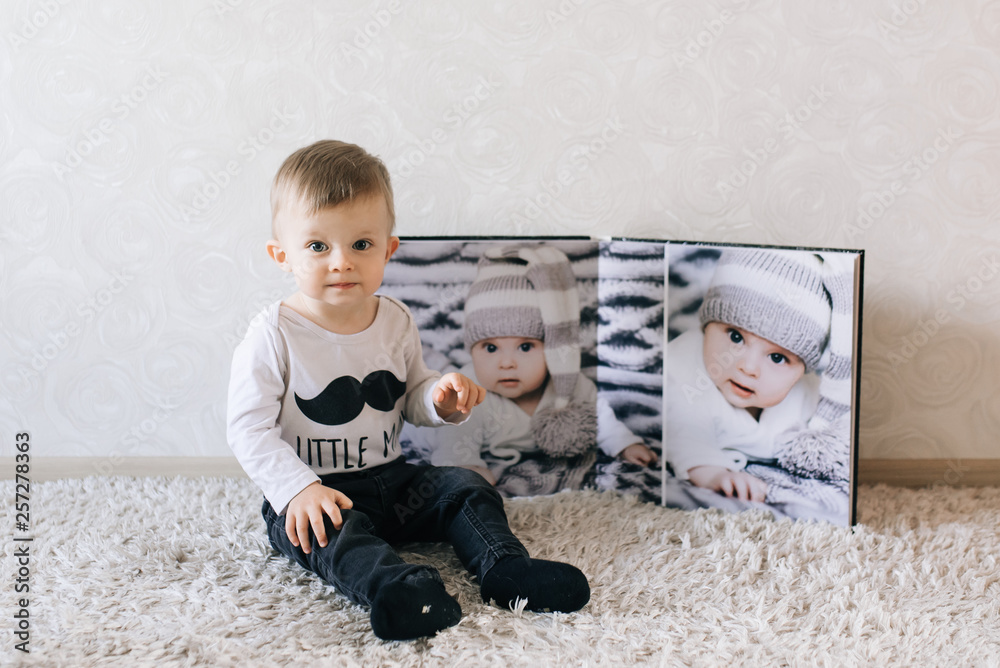 Cute baby sitting on the background of a large stylish photo book with your photos
