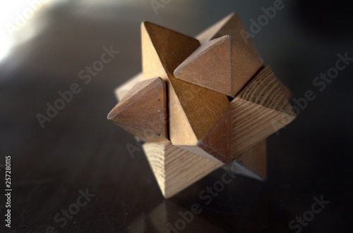 Wooden puzzle on flat glass surface. Geometric wooden figure. Solve problem.