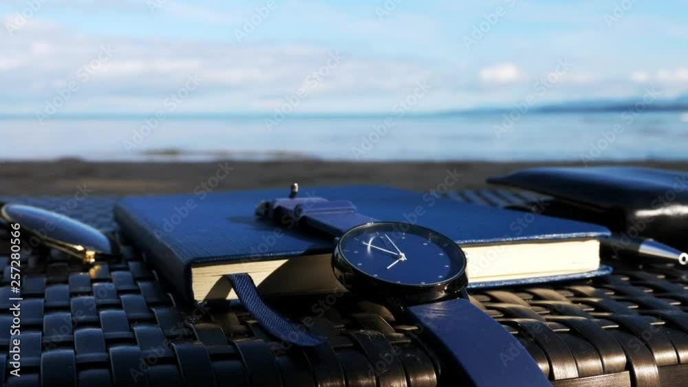close time at watch at working table with notebook , seascape background.