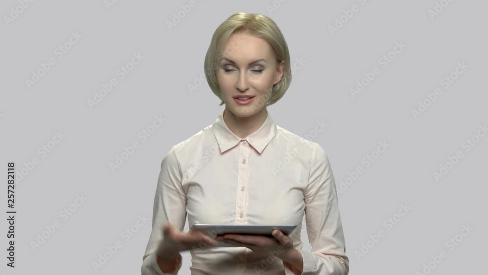 Business woman speaker holding pc tablet. Portrait of successful business coach against gray background.