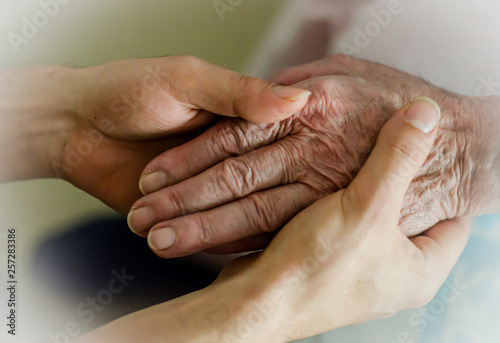 Elderly hand holding grandchild's hand.