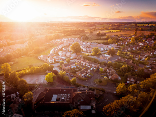 Sun setting with atmospheric effect over traditional British houses and tree lined streets. Dramatic, warm lighting creates a homely mood. Very typically English houses that are over 100 years old.