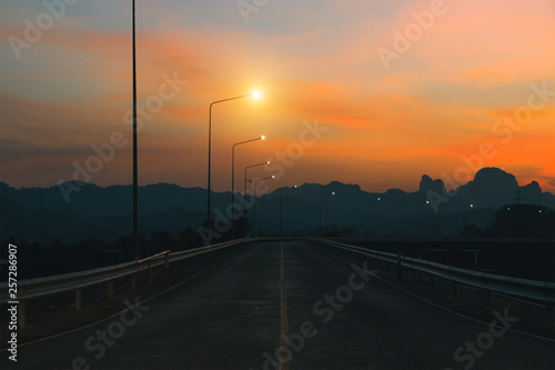 Mountain highway. Amazing landscape with rocks, sunset sky and asphalt road going to horizon at the evening. Vintage toning. Summer adventure background. Travel by car.