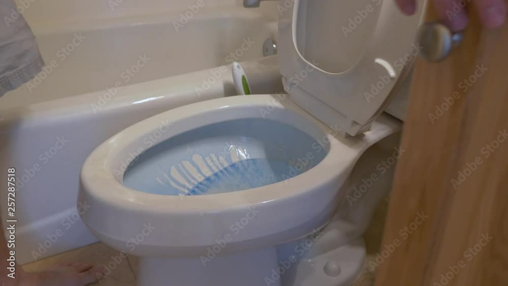 man puts toilet bowl cleaner into toilet and cleans the toilet with