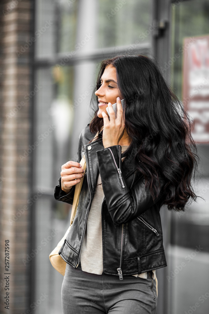 Fototapeta premium Latin woman with smartphone speak with friends