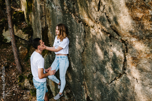 A man and woman stand near a large rock. stone. A young, stylish, love couple looks at each other, full length. Close up. Nature autumn. Side view.